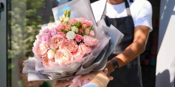 Woman buyer takes a beautifully formed bouquet in colored wrapping paper